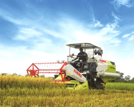 A Claas Rice Harvester in action, skillfully harvesting mature rice plants in a sprawling rice field.
